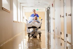 Sodexo hospital porter pushes a patient down a corridor